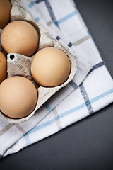 Image showing Fresh organic eggs in cardboard box an linen towel closeup on ba