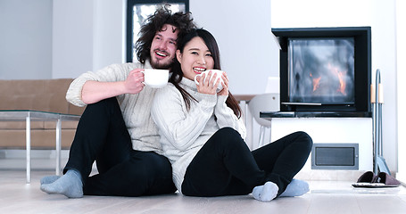 Image showing multiethnic romantic couple  in front of fireplace