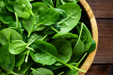 Image showing Fresh spinach leaves on wooden background. Healthy vegan food. Top view