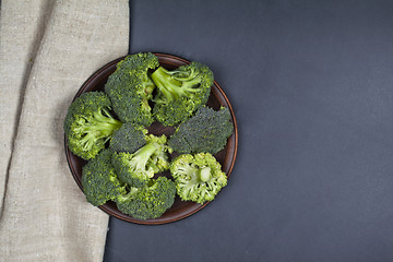 Image showing Fresh green organic broccoli in brown plate and linen napkin.