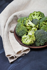 Image showing Fresh green organic broccoli in brown plate and linen napkin 