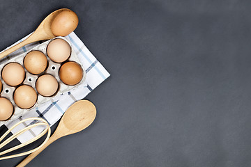 Image showing Fresh eggs and kitchen utensil on backboard background. 