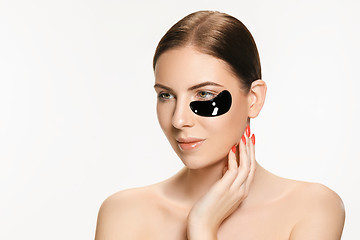 Image showing Young beautiful woman applying a mask for the face of the therapeutic black mud. Spa treatment