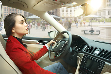 Image showing Driving around city. Young attractive woman driving a car