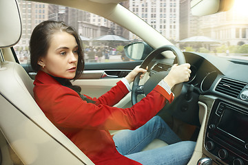 Image showing Driving around city. Young attractive woman driving a car