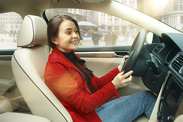 Image showing Driving around city. Young attractive woman driving a car