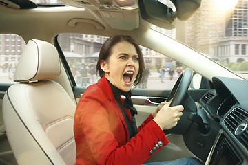 Image showing Driving around city. Young attractive woman driving a car