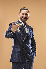 Image showing Smiling young businesman with glass of champagne standing and celebrating over pastel background