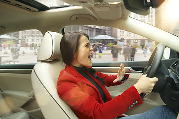 Image showing Driving around city. Young attractive woman driving a car