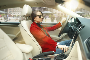 Image showing Driving around city. Young attractive woman driving a car