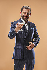 Image showing Smiling young businesman with glass of champagne standing and celebrating over pastel background