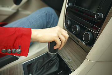 Image showing Close up of young woman shifting gears on gearbox and driving car.