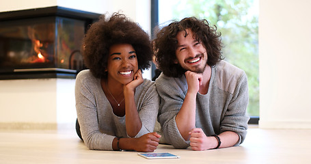 Image showing multiethnic couple lying on the floor  in front of fireplace