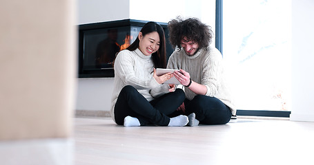 Image showing Young Couple using digital tablet on the floor