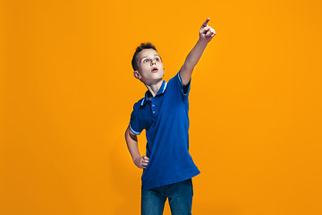 Image showing The happy teen boy pointing to you, half length closeup portrait on orange background.