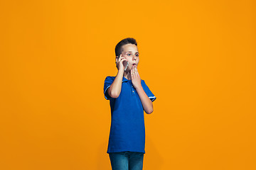 Image showing The happy teen boy standing and smiling against orange background.