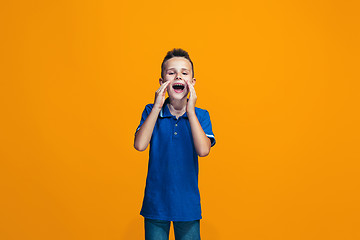 Image showing Isolated on orange young casual teen boy shouting at studio