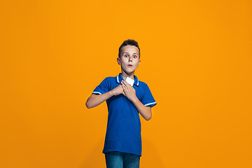 Image showing The happy teen boy standing and smiling against orange background.