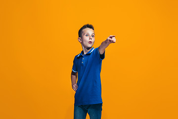 Image showing The happy teen boy pointing to you, half length closeup portrait on orange background.