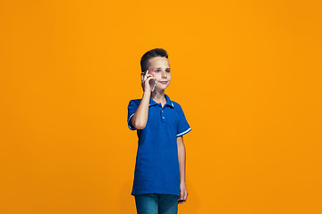 Image showing The happy teen boy standing and smiling against orange background.