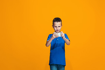 Image showing The happy teen boy standing and smiling against orange background.