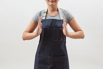 Image showing Woman chef cook in a denim apron holds your empty hands open on a white background. Mock up copy space concept .