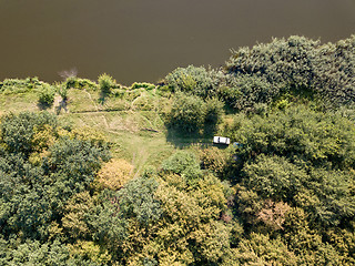 Image showing Aerial view from drone recreation place on a bank of river. Top view green trees, meadow and white car. Top view.