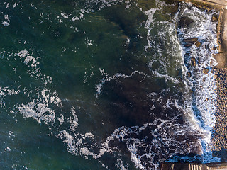 Image showing Aerial top view to a stone beach of seashore, turquoise water and crashing foam waves. Top view from drone. Place for text.