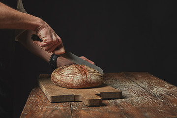 Image showing Man slicing tasty fresh bread.