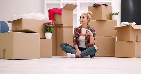 Image showing woman with many cardboard boxes sitting on floor