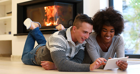 Image showing multiethnic couple using tablet computer on the floor