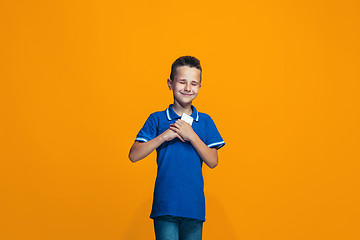 Image showing The happy teen boy standing and smiling against orange background.