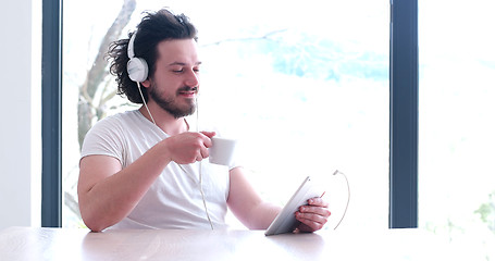 Image showing young man listenig music on tablet at home