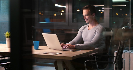 Image showing man working on laptop in dark office