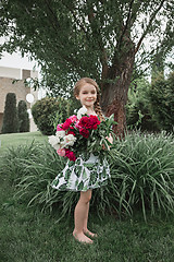 Image showing Portrait of smiling beautiful teenage with bouquet of daisies, against green of summer park.