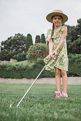 Image showing Little girl just swing golf ball on golf course fairway