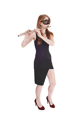 Image showing Woman standing, playing the flute wearing a mask
