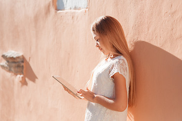 Image showing beautiful young woman in white dress using tablet