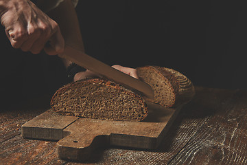 Image showing men\'s hands cut homemade a dark bread