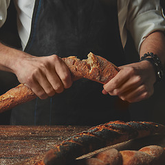 Image showing Male hands break the baguette