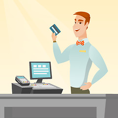 Image showing Caucasian cashier holding a credit card.