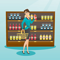 Image showing Woman holding shopping basket and bottle of sauce.