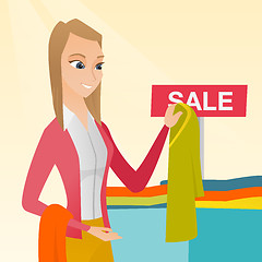 Image showing Young woman choosing clothes in the shop on sale.