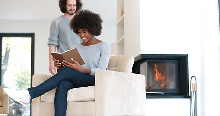 Image showing multiethnic couple hugging in front of fireplace