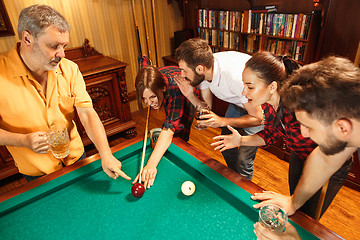 Image showing Young men and women playing billiards at office after work.