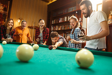 Image showing Young men and women playing billiards at office after work.