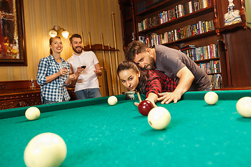 Image showing Young men and women playing billiards at office after work.