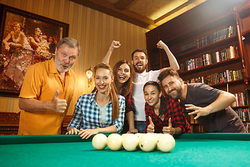 Image showing Young men and women playing billiards at office after work.