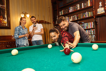 Image showing Young men and women playing billiards at office after work.