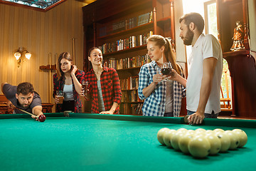 Image showing Young men and women playing billiards at office after work.